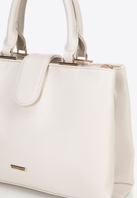 Borsa a mano in pelle bianca con design strutturato, doppio manico e minuteria color oro. Presenta una chiusura a patta e dettagli con il logo del marchio.