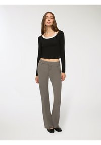 Crop top nero a maniche lunghe con scollo bianco, abbinato a pantaloni grigi chiari su misura. Tessuto liscio con un design aderente e gambe dritte.