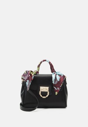 Mustalla nahkalaukku, jossa on kultainen solki, ja siinä on värikkäällä kuviolla varustettu huivi solmittuna kahvan ympärille sekä irrotettava olkahihna.