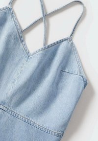 Vestido de denim azul claro con escote en V, tirantes de espagueti entrelazados y detalles de costura sutil. Textura suave con un diseño casual.