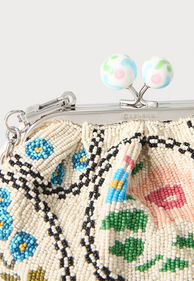 Gros plan d’une bourse perlée avec des motifs floraux, un fermoir en métal et deux sphères blanches décoratives aux couleurs pastel sur le dessus.