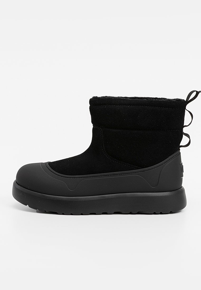Zwarte enkelboot met een gladde rubberen zool, zachte textielen bovenkant en een gewatteerde kraag. Inclusief een trekband aan de achterkant voor gemakkelijk aan- en uittrekken.