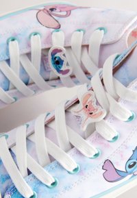 Baskets en toile avec un design tie-dye pastel, accents de personnages, lacets blancs, œillets et semelle bleu clair.