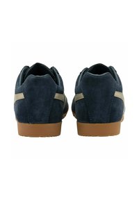 Sneakers blu in suede con suola in gomma color beige, caratterizzati da una striscia chiara lungo il tallone e una forma arrotondata. Design delle stringhe standard.