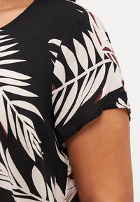 Schwarzes kurzärmliges Oberteil mit einem weißen und kastanienbraunen Palmenblattmuster, aus leichtem Stoff mit samtiger Textur und rundem Halsausschnitt.