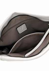 Interno di una borsa a tracolla in pelle bianca con una tasca con zip e foderata in grigio. Include un piccolo etichetta in pelle e una cucitura decorativa sui bordi.