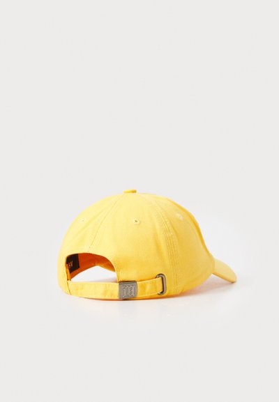 Gul bomuldsbaseballcap med justerbar rem, der har en metalspænde og bagved ventileringshuller. Glat stofstruktur.