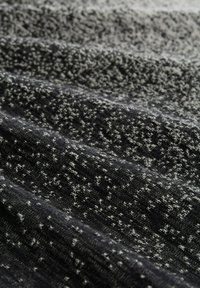 Strukturierter Strickstoff in Schwarz und Grau, mit einem gesprenkelten Muster aus abwechselnd hellen und dunklen Fäden, die Tiefe und Interesse erzeugen.