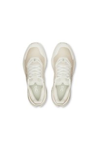Scarpe da ginnastica beige con tomaia in rete, lacci tonali, suola in gomma morbida e colletto imbottito. Presentano un logo sulla linguetta e sul tallone.