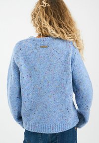 Hele sinine kudumiskoorega kampsun pehme tekstuuriga, millel on mitmevärvilised täpid, ümmargune kaelus ja soonikkoes äär. Brändi silt on nähtav taga.