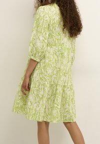 Grünes und weißes gemustertes Kleid mit mehrlagigem Saum, strukturiertem Stoff und 3/4 Puffärmel. Verfügt über einen elastischen Taillenbund.
