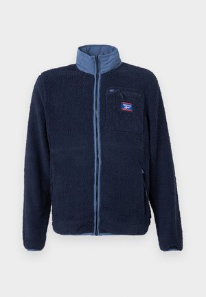 Navy fleece jacket with a light blue collar, front zipper, and zippered chest pocket. Textured fabric with a soft, fuzzy appearance.