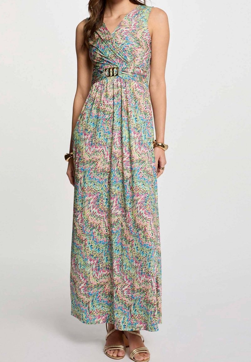 Robe longue sans manches à motif zigzag multicolore, col en V et détail ceinture, portée avec des sandales dorées et des bracelets assortis.