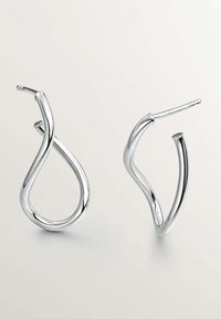 Pendientes de aro plateados con un diseño abstracto retorcido. Textura suave, forma esbelta, que presenta un vástago puntiagudo para el cierre.