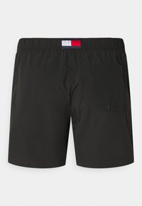 Shorts de bain noirs en matériau léger, dotés d'une taille élastique, d'une poche au dos et d'un petit logo tricolore au dos.