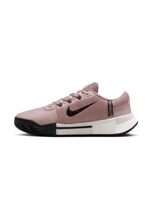 Chaussure de sport Nike rose clair avec swoosh noir, embout noir, semelle intermédiaire blanche et design bas, montrée de profil sur fond blanc.