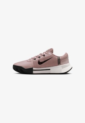 Chaussure de sport Nike rose clair avec swoosh noir, embout noir, semelle intermédiaire blanche et design bas, montrée de profil sur fond blanc.