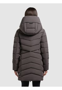 Chaqueta de plumas larga y gris oscuro con capucha, que presenta un diseño de acolchado en forma de chevrón y un dobladillo con cremallera. Incluye un detalle de logo cerca del dobladillo.