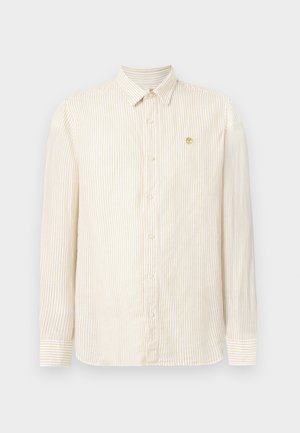 Beżowa i biała koszula na guziki z długimi rękawami, kołnierzykiem, mankietami oraz małym złotym logo drzewa na lewej piersi.