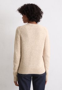 Beige gebreide trui met een textuurafwerking, voorzien van een ronde hals en geribde manchetten en zoom. Het ontwerp is eenvoudig en aansluitend op de taille.