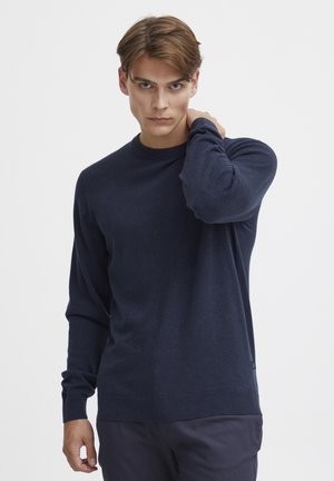 Marineblå crew-neck genser laget av mykt stoff, med lange ermer og ribbestrikkede mansjetter og kant, med en liten logomerking nederst.