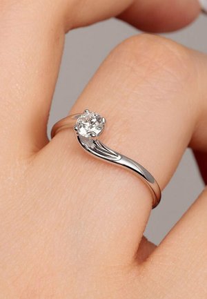 Silberring mit einem zentralen runden Diamanten, ausgestattet mit einem glatten, polierten Band, das sich leicht krümmt und die Brillanz des Diamanten hervorhebt.