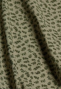 Katoenen stof met een licht olijfgroene achtergrond, met kleine donkergroene bloemen- en bladpatronen over het oppervlak. Zachte textuur.