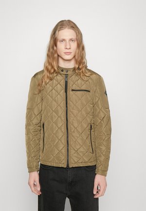Chaqueta acolchada de color verde oliva con cuello alto, cierre frontal de cremallera y bolsillos con cremallera. Presenta un tejido texturizado y una silueta ajustada.