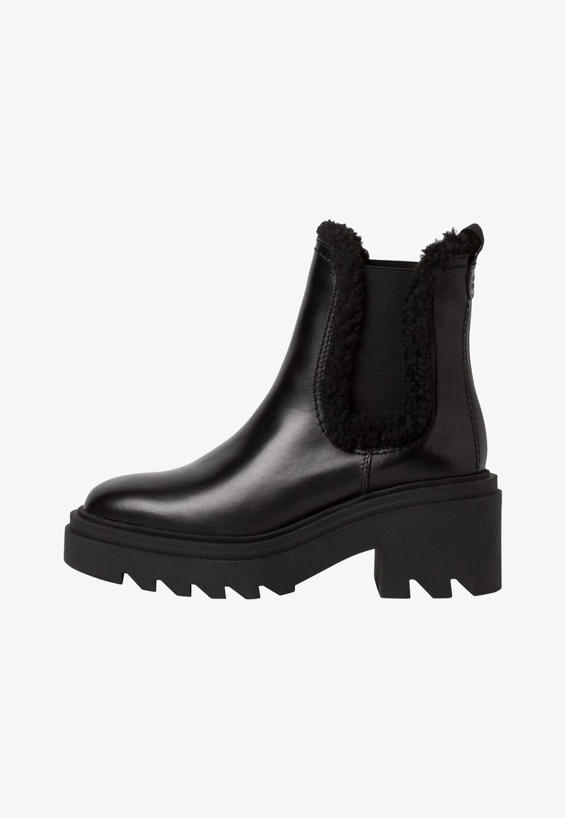 Bottines noires en cuir avec une semelle en caoutchouc noire épaisse, des bordures duveteuses sur les côtés, des panneaux élastiques et un design à bout arrondi.