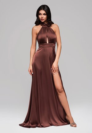 Robe de soirée en satin brun avec un col halter, une découpe en trou de serrure et une fente sur le côté. Présente un tissu froncé et un accent floral au niveau du col.