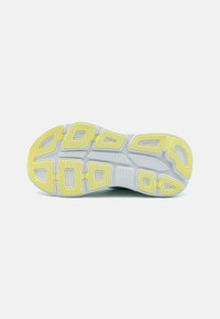 Semelle de chaussure avec un design segmenté, principalement blanche avec des accents jaunes. Caoutchouc texturé offrant adhérence et durabilité.
