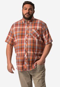 Košile krátkého rukávu s kostkovaným vzorem v oranžové, modré a béžové barvě. Obsahuje límec na knoflíky a náprsní kapsu. Nosené s kalhotami světlé barvy.