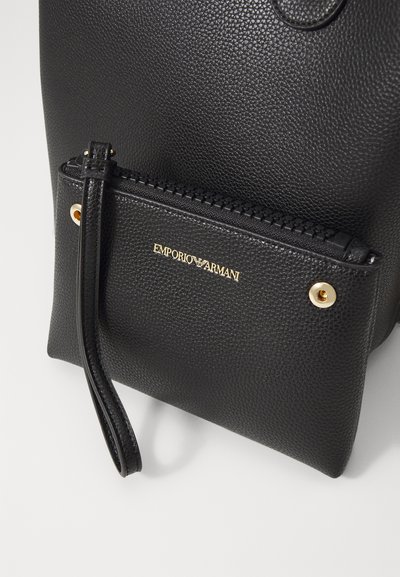 Borsa a mano in pelle nera con superficie testurizzata, hardware dorato e tasca con zip caratterizzata da un logo impresso.
