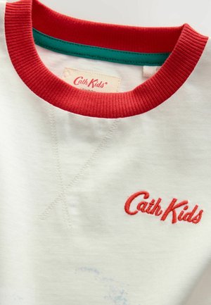 Kratka bela majica s kratkimi rokavi z rdečim rebrastim ovratnikom, notranji ovratnik v teal barvi, izvezen logotip "Cath Kids" in vidne šive.