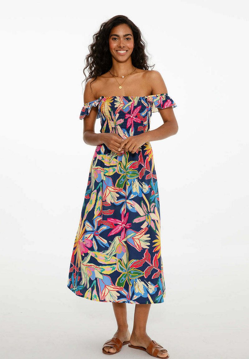 Maxi šaty bez ramínek v námořnické modři s živými květinovými vzory. Mají volánové rukávy a přiléhavý korzet. Délka šatů sahá až k ankles.