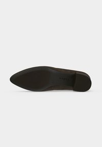 Semelle d'une chaussure marron foncé à bout pointu avec talon texturé et grip en caoutchouc marqué sur fond blanc uni.