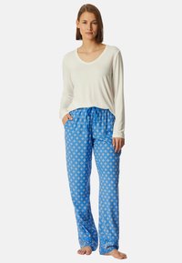 Witte langharige top met een ronde hals, gecombineerd met blauwe, gestreepte pyjamabroek met een bloemenpatroon en elastische tailleband.
