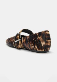 Platte schoen in luipaardprint met spitse neus, zwarte zool en zilveren gespband over de bovenkant tegen een witte achtergrond.