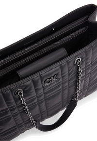 Black quilted handbag made of synthetic material. Features a silver-tone chain handle, a sleek design, and multiple interior compartments.