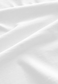 Weißer Stoff mit glatter Textur, der subtile, gleichmäßig verteilte Falten aufweist. Das Material wirkt leicht und weich.