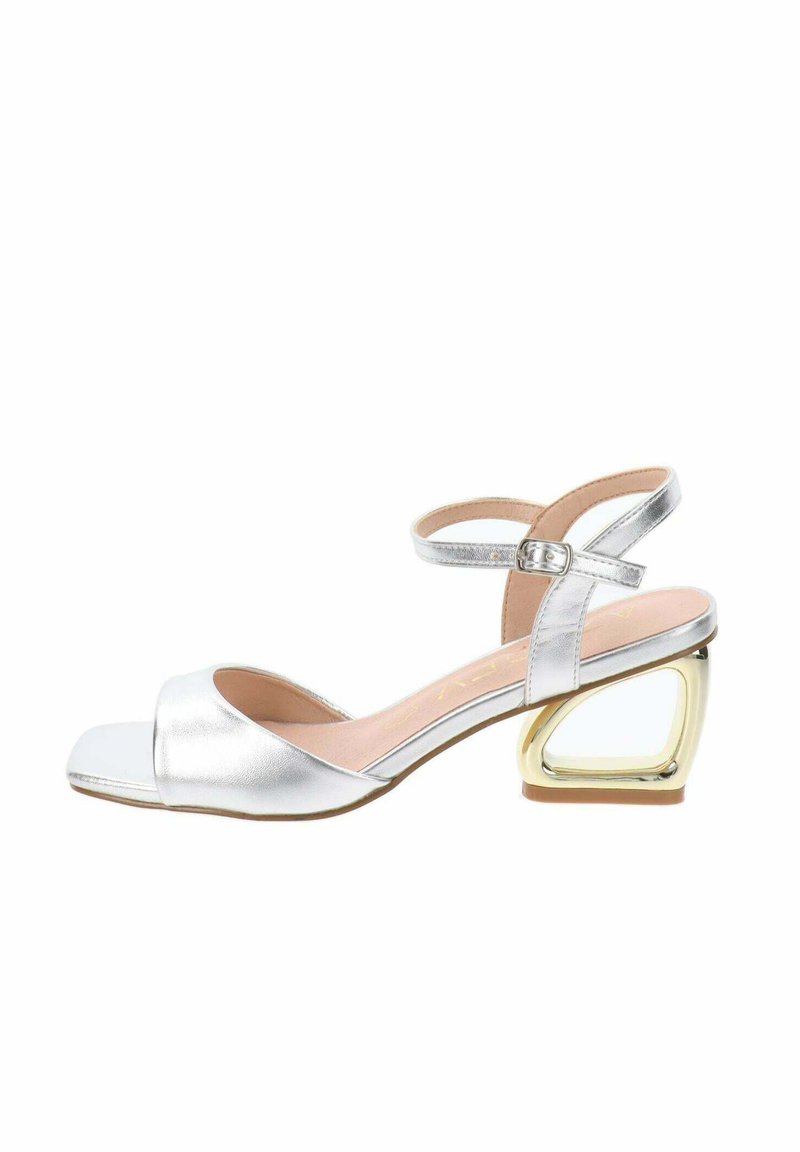Sandal aperto argento metallico con cinturino alla caviglia, caratterizzato da un tacco geometrico a blocco dorato a contrasto e una superficie liscia.