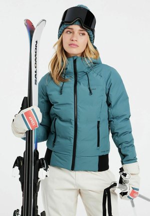 Teal isolierte Skijacke mit Reißverschlusstaschen, schwarzen Akzenten und Kapuze mit Kordelzug. Weiße Skihandschuhe mit roten, blauen und grünen Streifen.