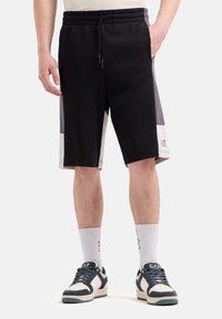 Shorts sportivi neri e grigi con vita regolabile, pannelli laterali a blocchi di colore e un dettaglio del logo vicino all'orlo.