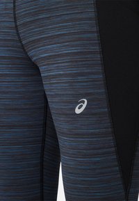 Czarno-niebieskie, paskowane legginsy sportowe z teksturowaną powierzchnią, z logo na udzie oraz kontrastującymi czarnymi panelami bocznymi.