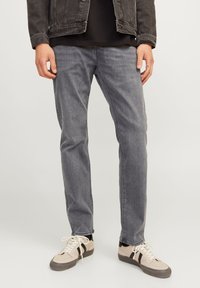 Gray denim jeans with a straight cut, featuring subtle fade details and stitched seams, paired with light-colored sneakers.