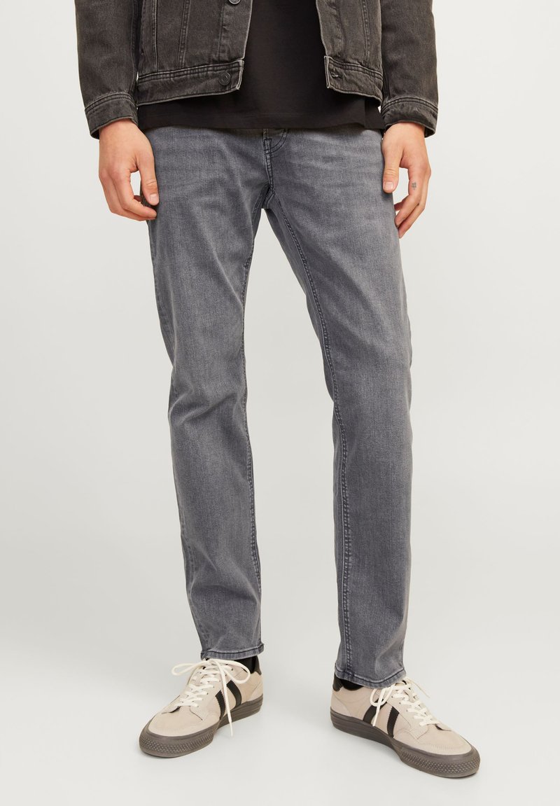 Gray denim jeans with a straight cut, featuring subtle fade details and stitched seams, paired with light-colored sneakers.