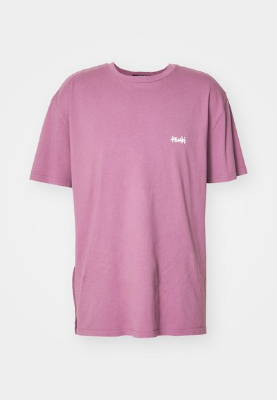 Camiseta de algodón rosa con mangas cortas, cuello redondo y un corte lateral; presenta un pequeño logo blanco en el lado izquierdo del pecho.