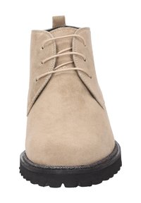 Stivaletto in camoscio beige con punta rotonda, lacci con tre occhielli e suola in gomma nera testurizzata. Presenta un'etichetta di manovra sul retro.