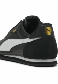 Baskets noires avec un dessus en cuir lisse, détail en rayure blanche, talon en daim texturé et accent logo doré. Semelle en caoutchouc pour une traction optimale.