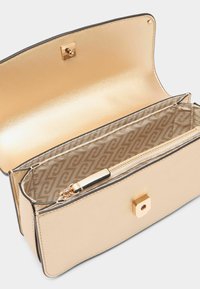 Beige kabelka z umělé kůže se čtvercovým klipem ve zlatém odstínu. Interiér obsahuje zipovou kapsu a podšívku s vzorovanou tkaninou.